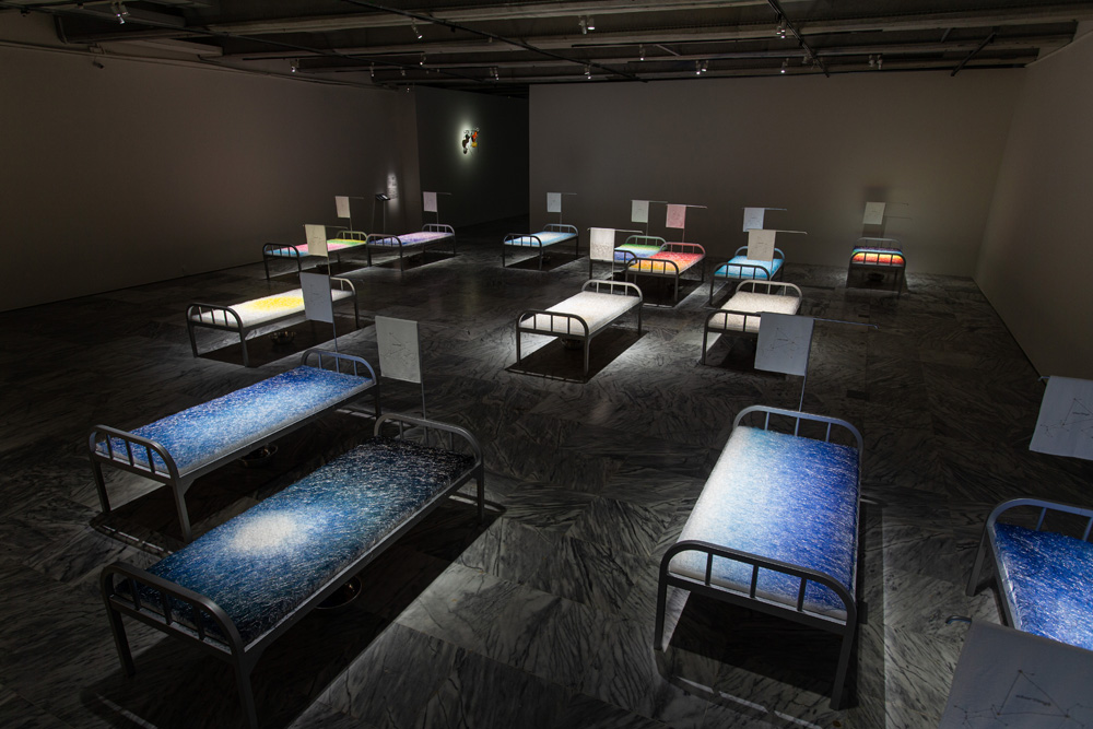 Chen Hui-Chiao  | A Room with a View Mixed mediums (needles, thread, fiberfill, military cots, embroidered towels, basins, toothbrushes, toothpaste, steel cups), 2018 16 pieces, 90 × 200 × 140 cm each  © Chen Hui-Chiao 的圖說